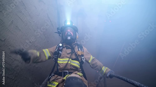Firefighter descends stairs during intense training drill in smoke-filled building at emergency services training facility