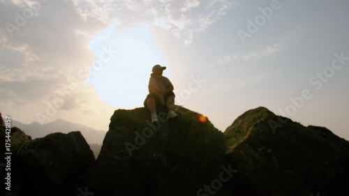 Silhouette of Woman Sitting on Mountain Peak and Looking into the Distance at Scenic Landscape