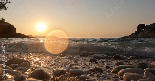 Golden sunset over rocky shore with calm waves and serene horizon