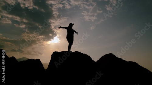A striking silhouette of a person achieving perfect balance while standing on a rock at sunset
