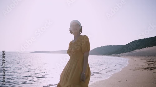 Playful Young Woman in Yellow Dress Spending Time by the Sea at Sunset