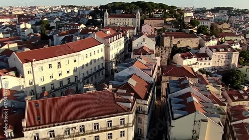 Cityscape aerial view features buildings with red tile roofs in warm light, clear skies