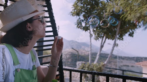 Woman Enjoying Weekend on Country House Terrace Blowing Soap Bubbles into Fresh Air