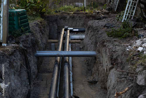 Pipes being installed in a trench in a residential backyard during the day