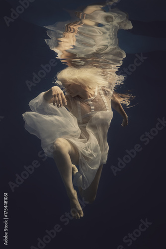 Woman with blonde hair in a lace white dress underwater