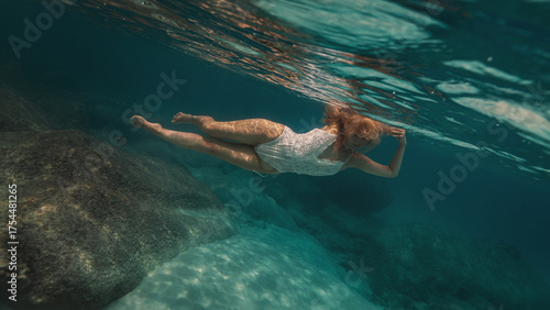 Woman with blonde hair in a lace white dress underwater