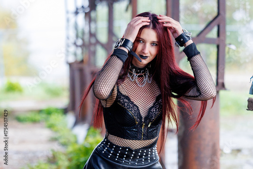 Gothic fashion woman in black leather outfit posing in industrial location