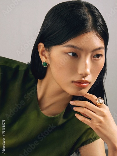 Woman in green top with elegant jewelry showcasing modern beauty.