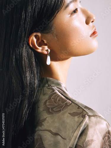 A profile portrait of a woman wearing floral patterned attire and elegant earrings.