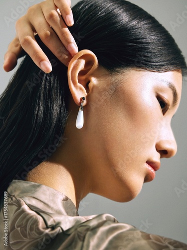 Profile shot of an Asian woman with elegant earrings and long hair.