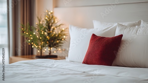 Cozy bedroom corner, pristine white sheets with white pillows and striking red square pillow, left nightstand small plant with warm yellow lights, window natural light