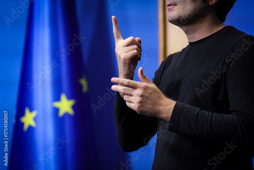 Deaf mute person gestures during a press conference with European Union flag in background