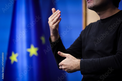 Deaf mute person gestures during a press conference with European Union flag in background