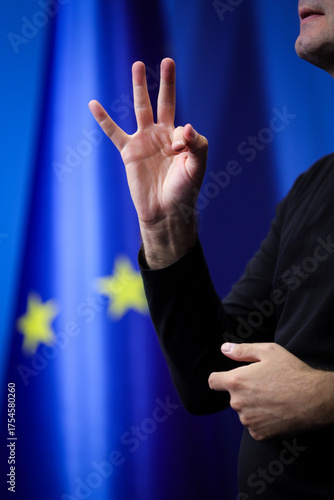 Deaf mute person gestures during a press conference with European Union flag in background