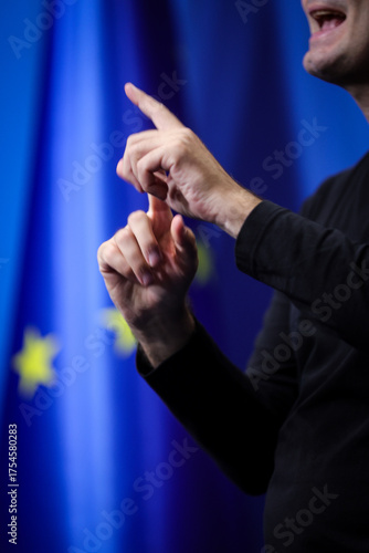 Deaf mute person gestures during a press conference with European Union flag in background