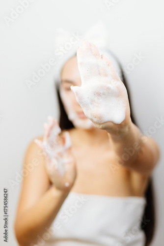 Woman applying facial foam on her face.. female applying Facial Cleanser. Young adult woman using foam cleanser for face skin cleaning. 
