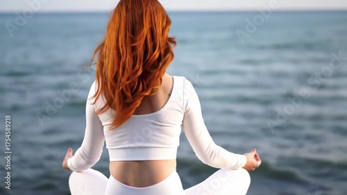 Woman Meditating by Ocean with Red Hair Facing Away
