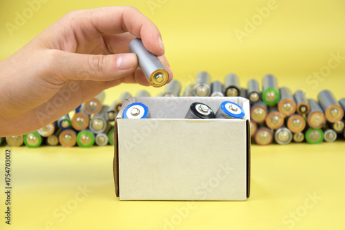 Used AA batteries and proper disposal of environmentally and soil toxic batteries on a green background.