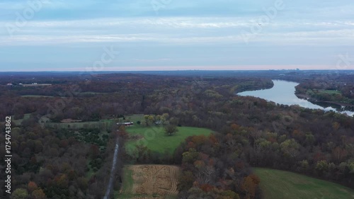 Aerial footage pulling back over rural farmland near Poolesville, Maryland, revealing the winding Potomac River and distant views of Northern Virginia beneath soft autumn skies.