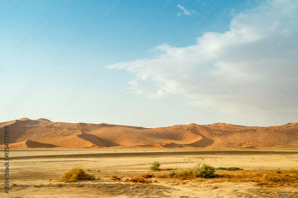 Fototapeta premium Rolling desert dunes near North Windhoek, Namibia, stretch beneath a dramatic cloudy sky