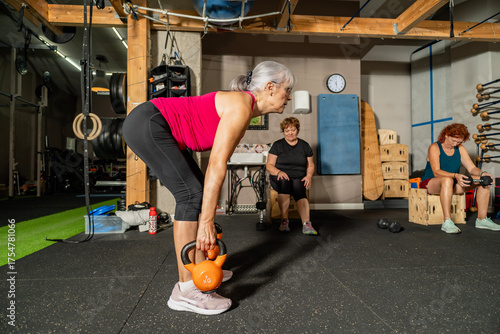 Senior woman lifting kettlebell during gym workout session