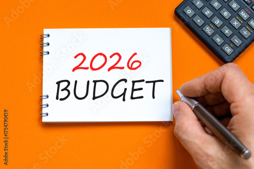 2026 Budget symbol. Concept words 2026 Budget on beautiful white note. Black calculator. Beautiful orange paper background. Businessman's hand. Business and 2026 budget concept. Copy space.
