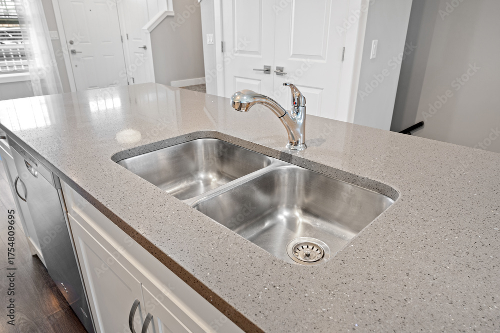 Fototapeta premium Stainless steel sink with a silver faucet sits on a granite countertop