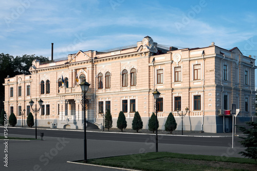 Historic neoclassical building with ornate facade and trees on a sunny day