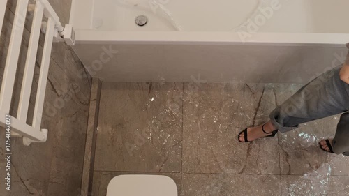 Bathroom flooding, plumbing failure, wet floor. Water leaking from bathtub flooding bathroom floor, with person stepping in water. Concept plumbing issue or home emergency.