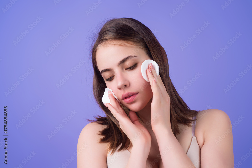 Obraz premium Woman cleansing skin by cotton pad sponge. Spa and wellness, skin care. Beauty routine. Beautiful girl cleaning face with cotton pad. Skin treatment, cosmetology.
