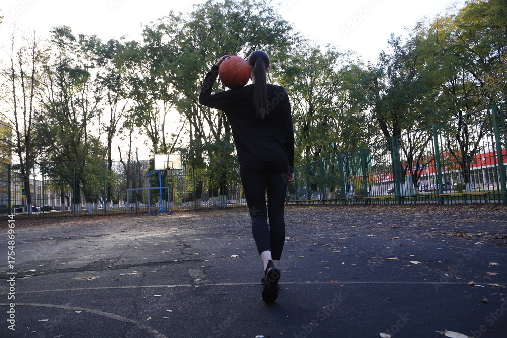 Fototapeta premium a young female athlete playing basketball from behind