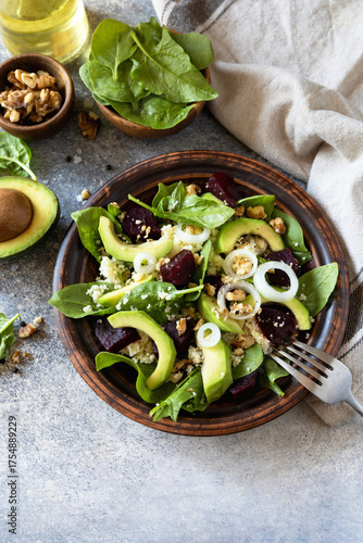 Canvastavla Couscous with avocado, beet, fresh spinach and dressing vinaigrette on a grey stone background