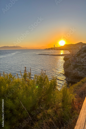 Sunset over the sea in Rincón de la Victoria, Malaga, Spain, with golden light reflecting on calm waves along the coast.