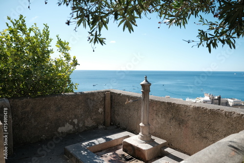 Panoramic view of the Amalfi coast, with a drinking fountain in the foreground.