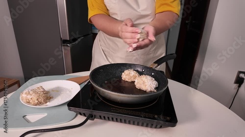 A woman in an apron cooks meatballs according to a recipe.