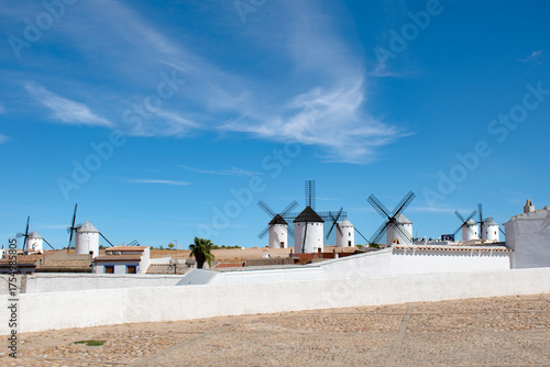 A white wall with La Mancha windmills behind it in Campo de Criptana, Ciudad Real province, Spain.