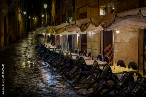 Night street view, empty restaurant terrace, plastic chairs and umbrellas, Italy