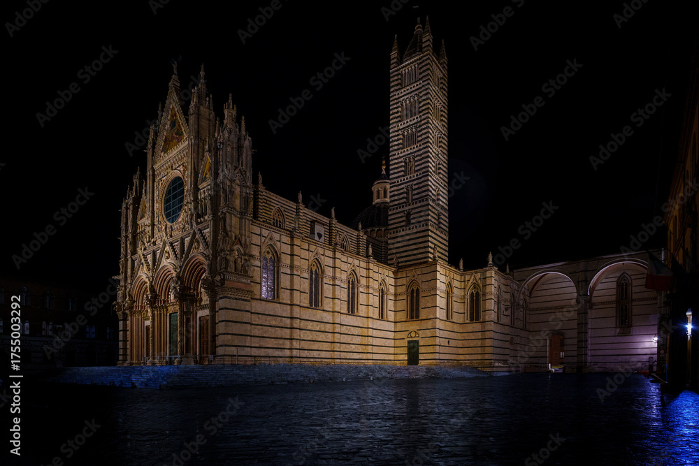 Naklejka premium Siena Cathedral illuminated at night, striped marble facade, vast empty square
