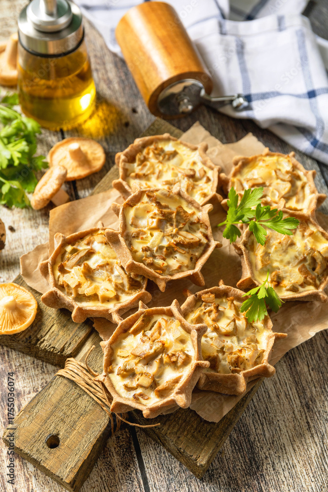 Fototapeta premium Rustic mushroom tartlets on wooden cutting board perfect for appetizers.