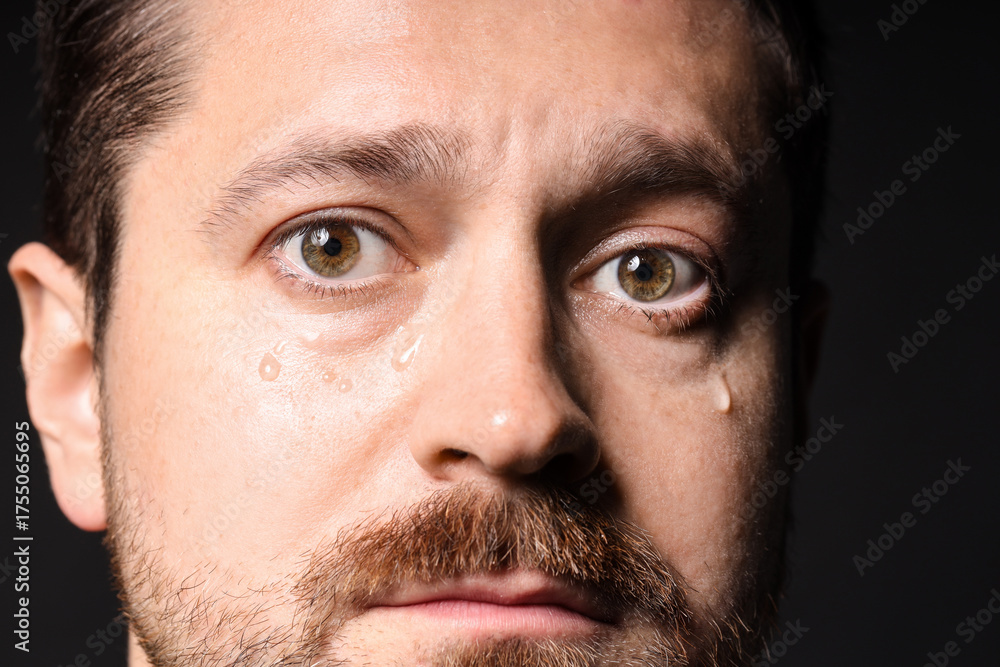 Fototapeta premium Sad man crying on black background, closeup