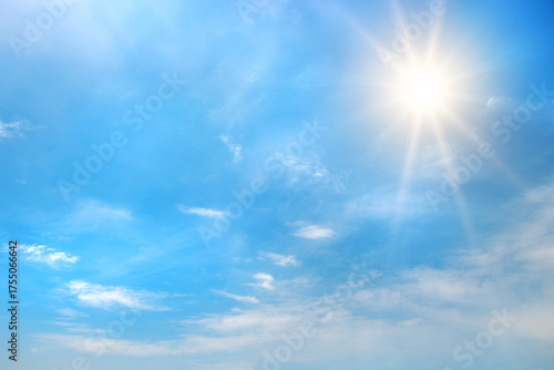 Bright blue sky with shining sun in upper corner and scattered white clouds illuminated by sun rays creating glowing daytime atmosphere with copy space