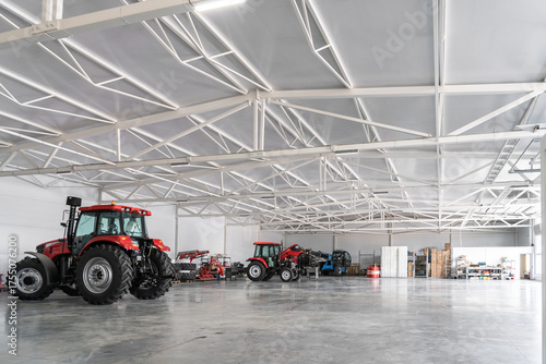 Modern agricultural warehouse with red tractors and farming equipment storage space.