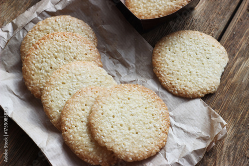 Sesame cookies lie on paper on a wooden table