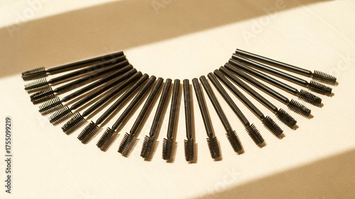 A neat fan of identical black makeup brushes arranged on a light surface, creating a sleek, organized look perfect for beauty, cosmetics, or makeup kit imagery.