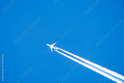 twin engined jet liner aircraft with contrails, in flight at high altitude, clear blue sky