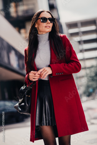 Elegant woman in red coat enjoying a stylish day out in city surroundings, showcasing high fashion and urban lifestyle