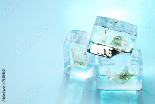 Euro bills in ice cubes on light blue background, space for text. Frozen money