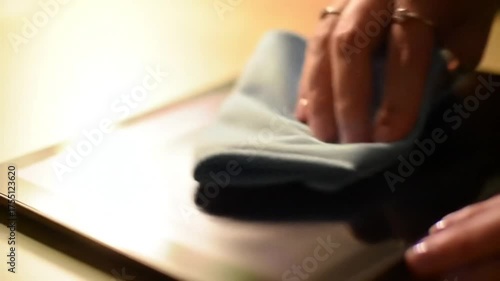 A close-up shot of a hand gently wiping a glass surface with a blue microfiber cloth.