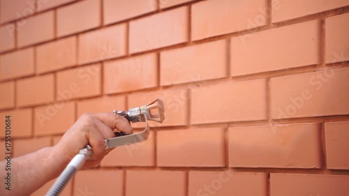Painting a brick wall using a spray gun. Renovation, construction, diy project, painting home.