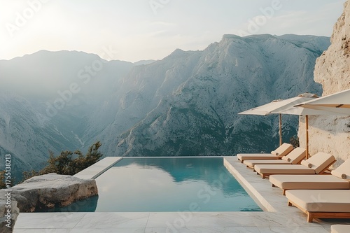Clifftop infinity pool with loungers facing dramatic mountains in hazy light